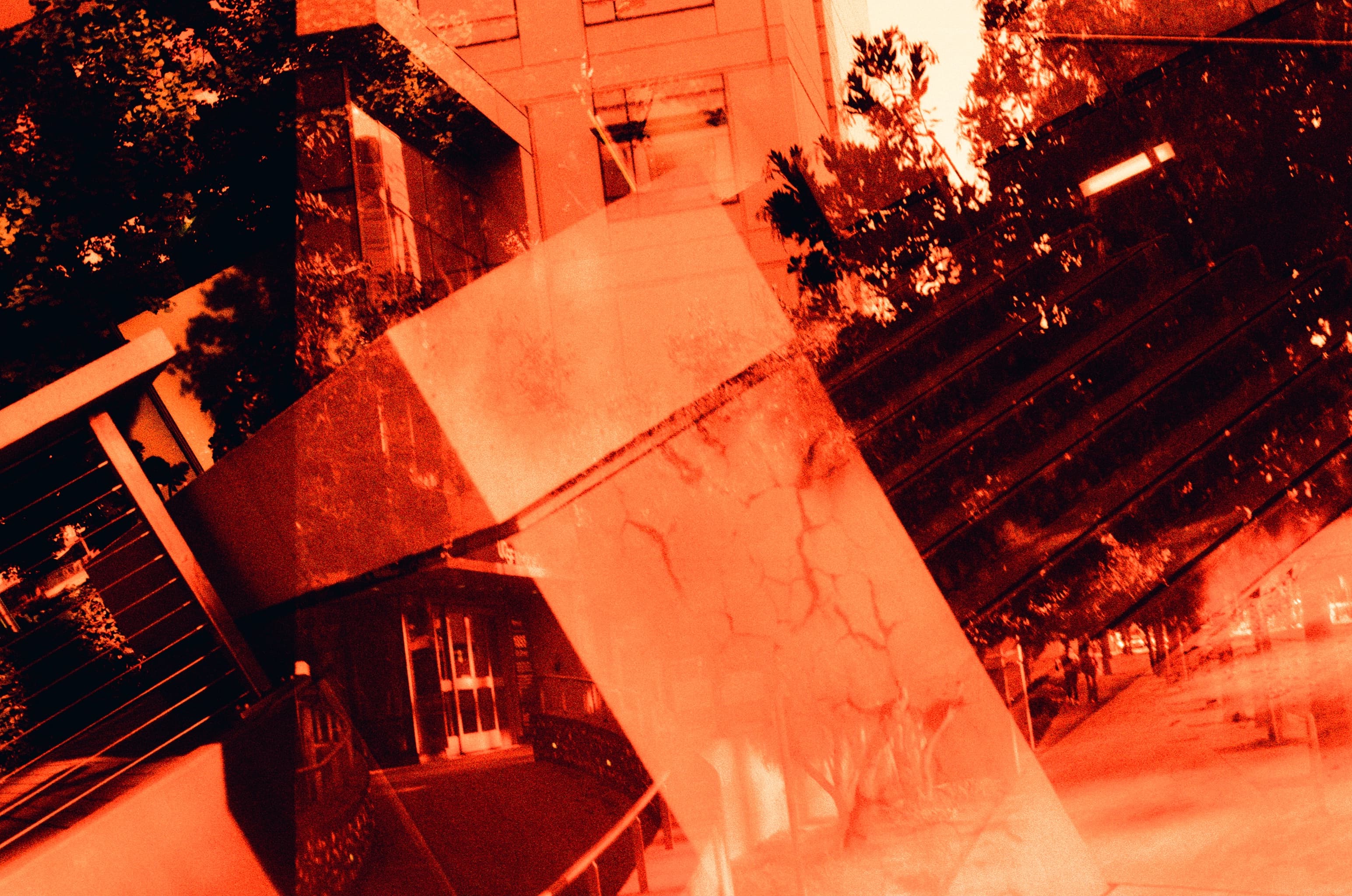 Architecture and sculpture layered in a red double exposure