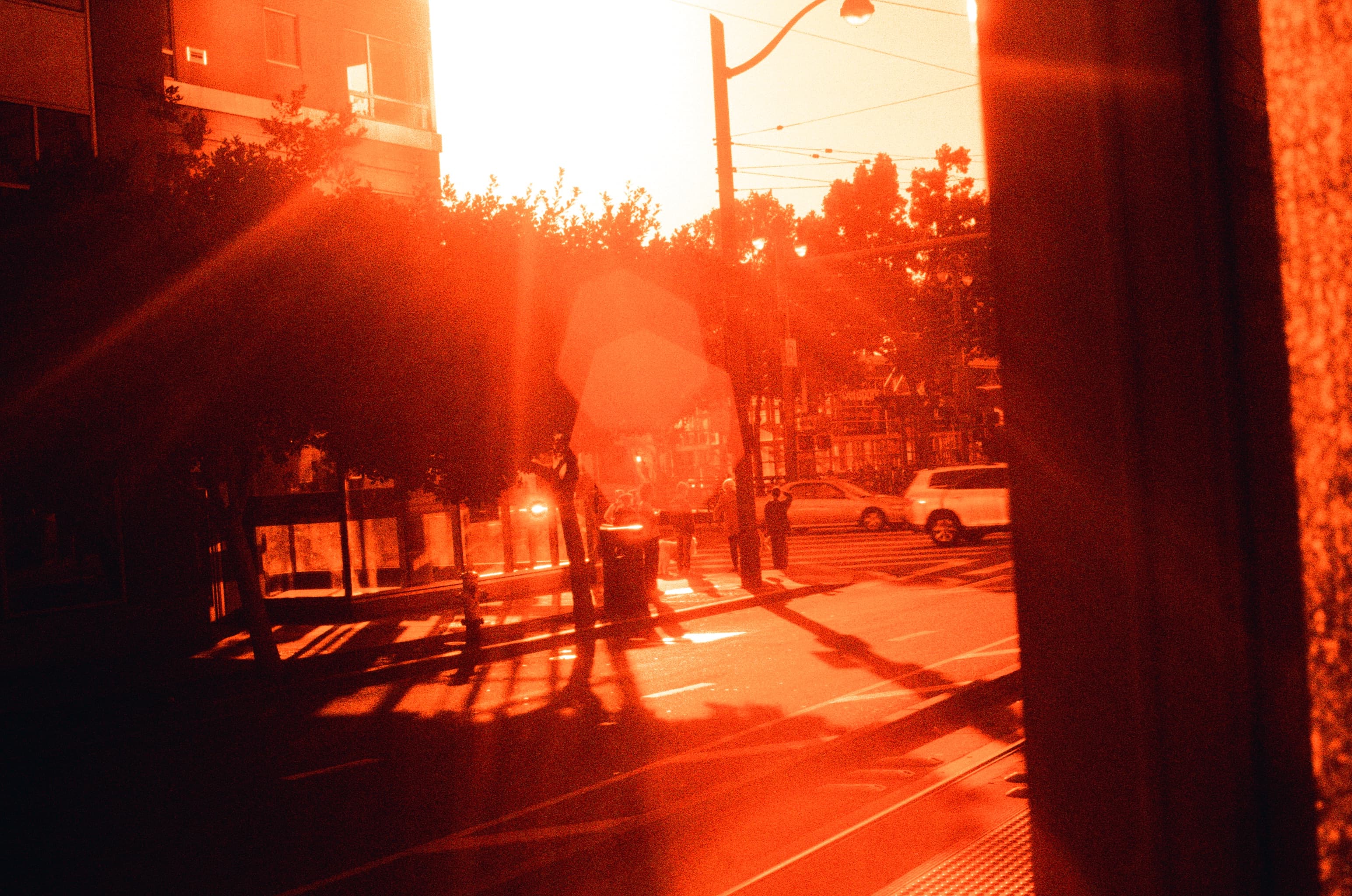 A city street crossed by red lens flare